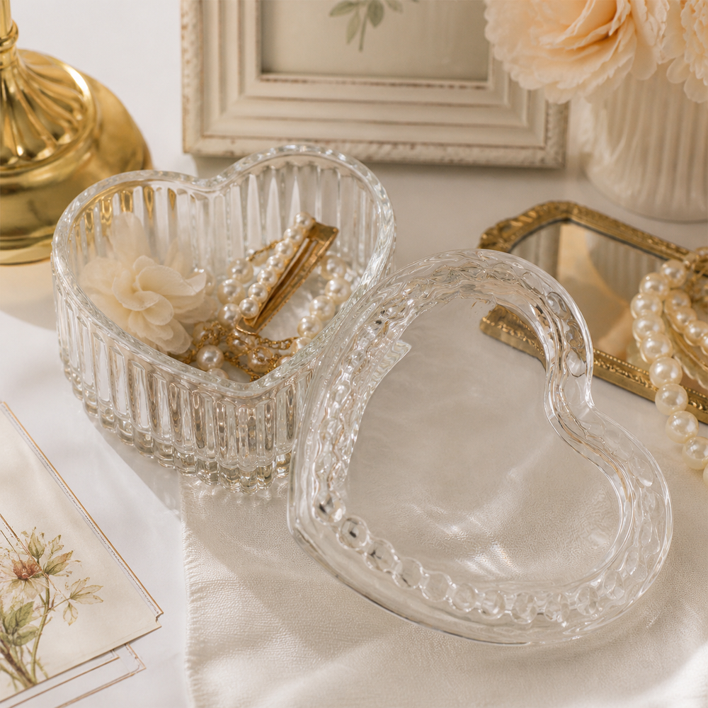 Open heart-shaped glass trinket box holding pearl jewelry