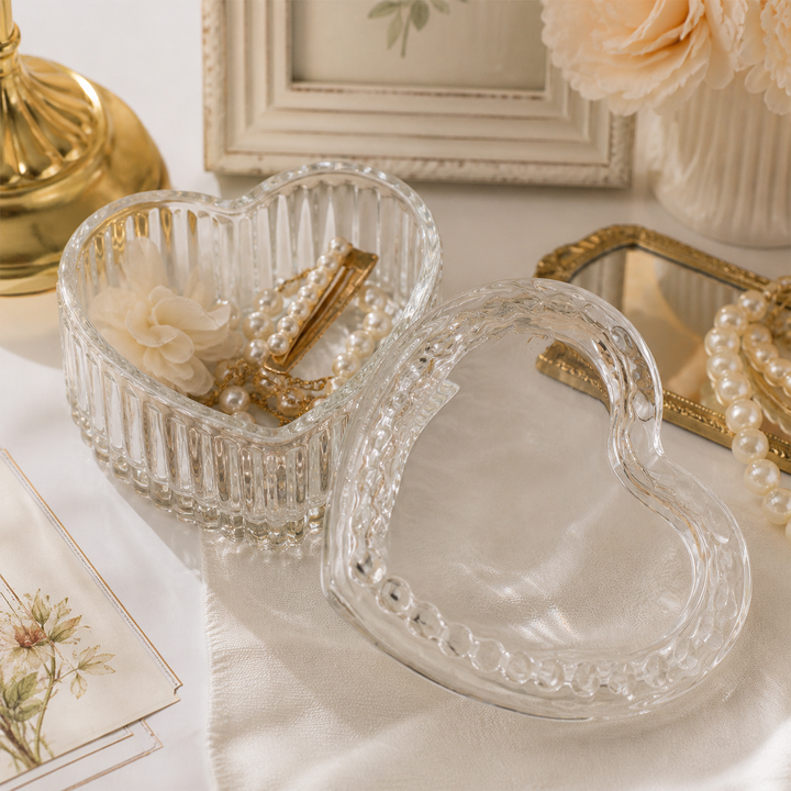 Open heart-shaped glass trinket box holding pearl jewelry