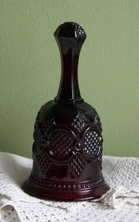 Glass Bell by Avon - Cape Cod Collection Ruby Color Sandwich Glass displayed on lace tablecloth.