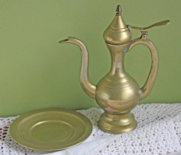 Vintage Brass Pitcher with Hinged Lid and Plate displayed on a lace cloth with green background.