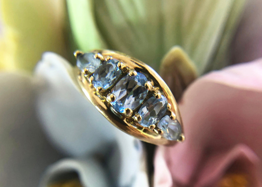 Vintage 10k Gold Ring with 5 Blue Topaz Stones featuring five oval blue topaz in a floral backdrop.