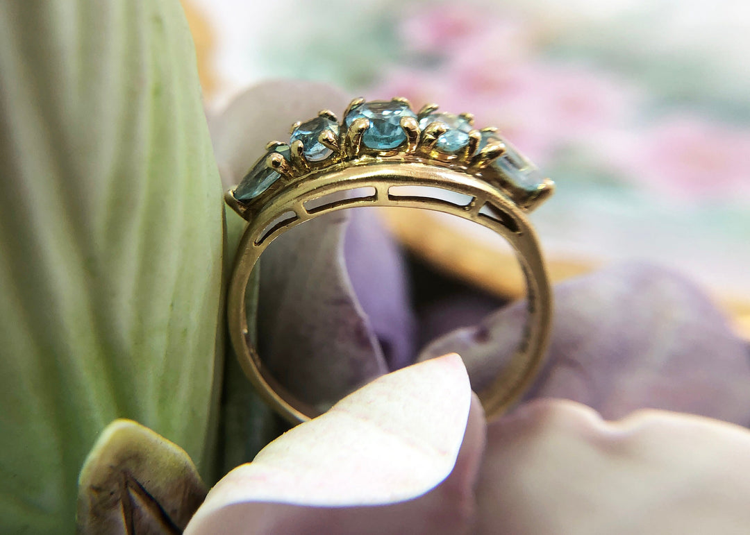 Vintage 10k Gold Ring with 5 Blue Topaz Stones on a floral background, showing off its elegant design.