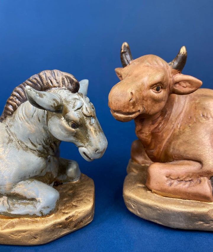 Handcrafted nativity figurines of a blue horse and a brown cow, featuring textured details and a decorative base.