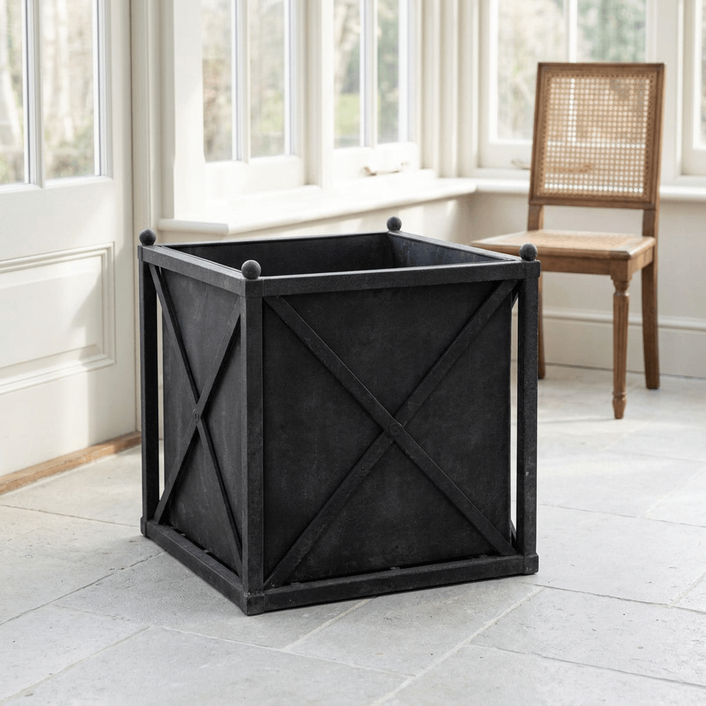 Orangerie Black Iron Estate Planter in Large, shown empty in a light-filled sunroom with X-braced panels and ball finials.