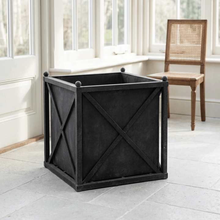 Orangerie Black Iron Estate Planter in Large, shown empty in a light-filled sunroom with X-braced panels and ball finials.