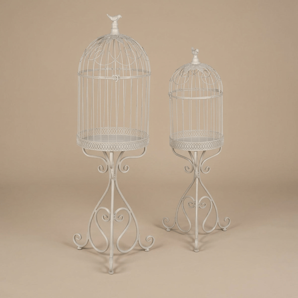 Two soft-white iron birdcage planters with domed tops, songbird finials, and scrollwork pedestal legs.