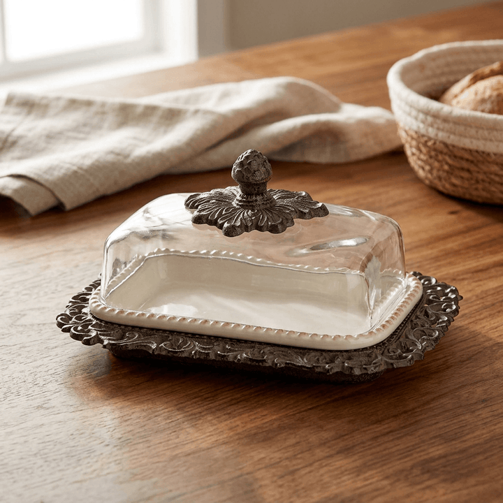 Bellavita butter dish on a wooden breakfast table beside linen and a bread basket