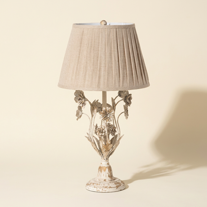 Antique White Floral Table Lamp with sculpted iron flowers and pleated linen shade against an ivory studio background.