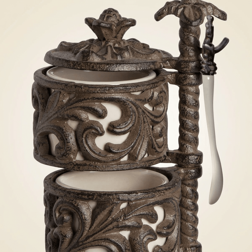 Close-up of Bellavita Spice Cellar cream ceramic jars, dark scrolling acanthus metal holders, ornate lid, and hanging spoon.