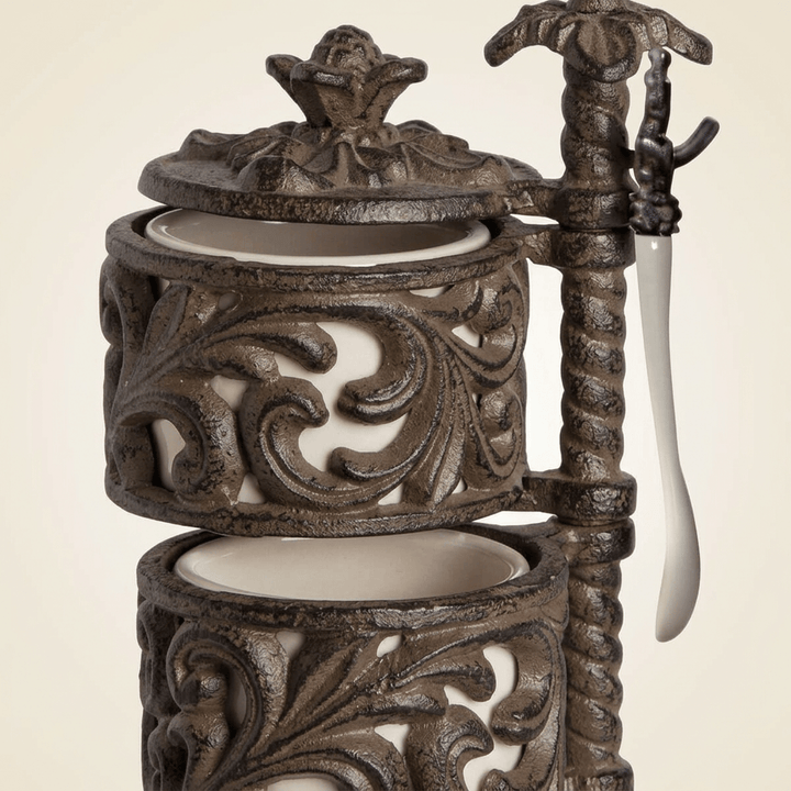 Close-up of Bellavita Spice Cellar cream ceramic jars, dark scrolling acanthus metal holders, ornate lid, and hanging spoon.
