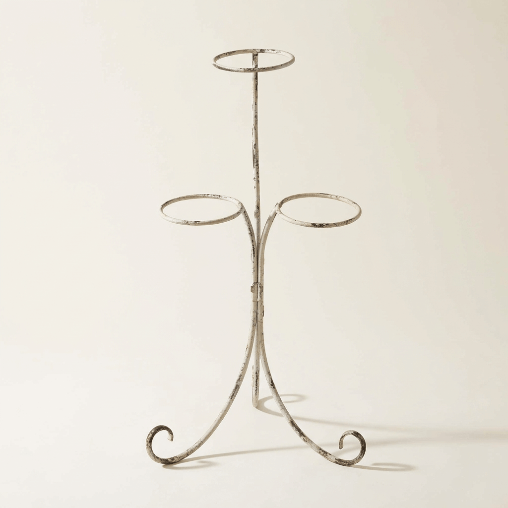 Antiqued ivory iron three-pot plant stand with open circular holders and curled feet on a neutral studio background.