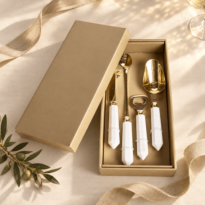 Four-piece marble and gold cocktail tool set presented in an open gold-toned gift box.