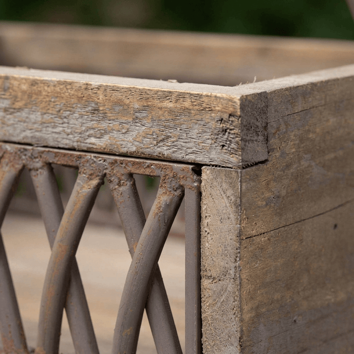 Close-up of the Bramley Garden Caddy's crisscrossed rust-toned iron lattice panel and weathered wood frame corner