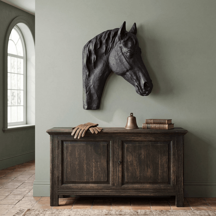 Charcoal horse-head sculpture displayed above a console against a muted sage wall in a traditional entryway.