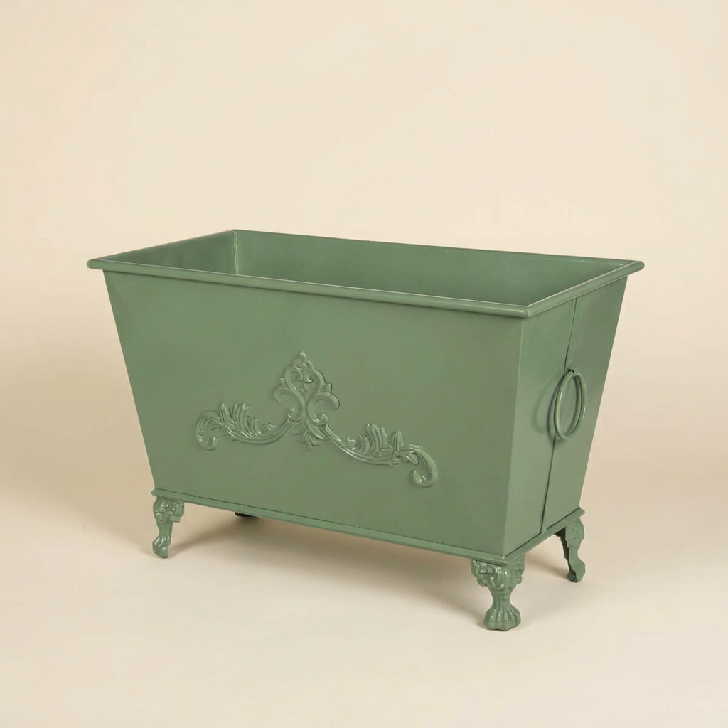 Studio view of the Aveline Scrollwork Metal Planter in Soft Garden Green showing its rectangular shape, scrollwork, ring handle, and ornate feet.