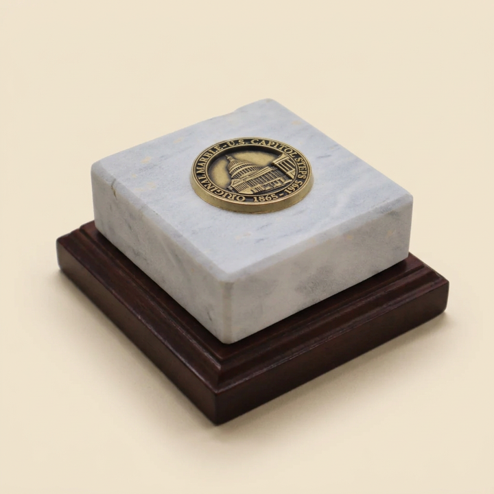 Square pale Capitol marble paperweight with round gold-toned medallion on a stepped walnut base