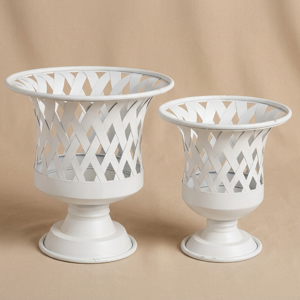 Empty large and small Villandry antiqued white woven iron urn planters against a warm beige studio background.