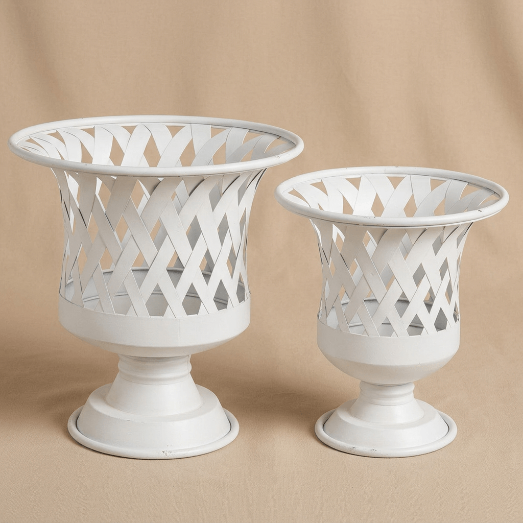 Empty large and small Villandry antiqued white woven iron urn planters against a warm beige studio background.