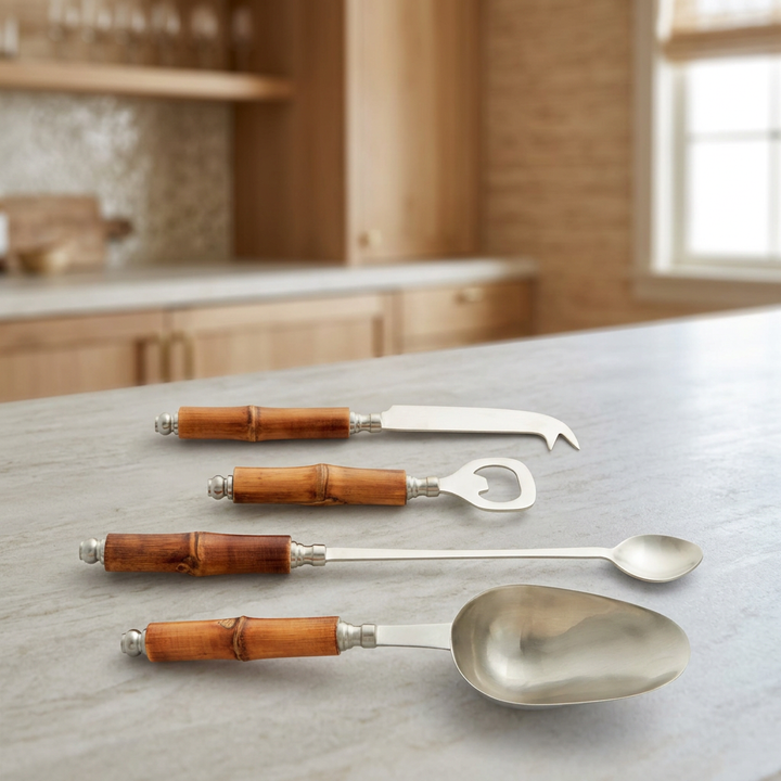 Bamboo-handled cocktail knife, bottle opener, bar spoon, and ice scoop styled on a pale stone bar surface.