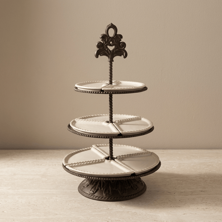 Bellavita three-tier stoneware server on a pale stone surface showing its decorative finial and dark metal pedestal