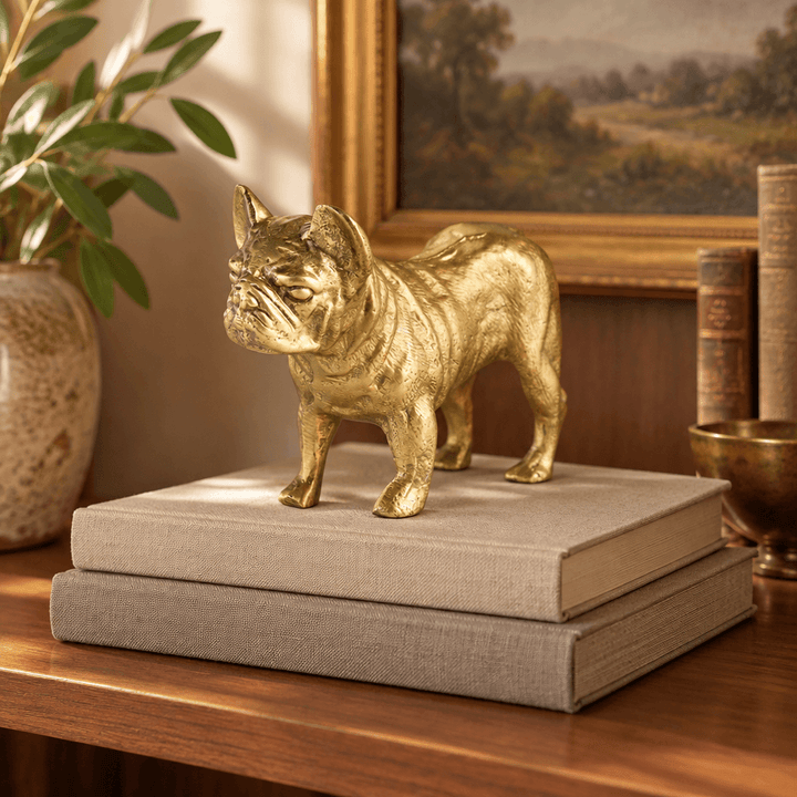 Gold bulldog sculpture styled on neutral books on a walnut bookshelf.