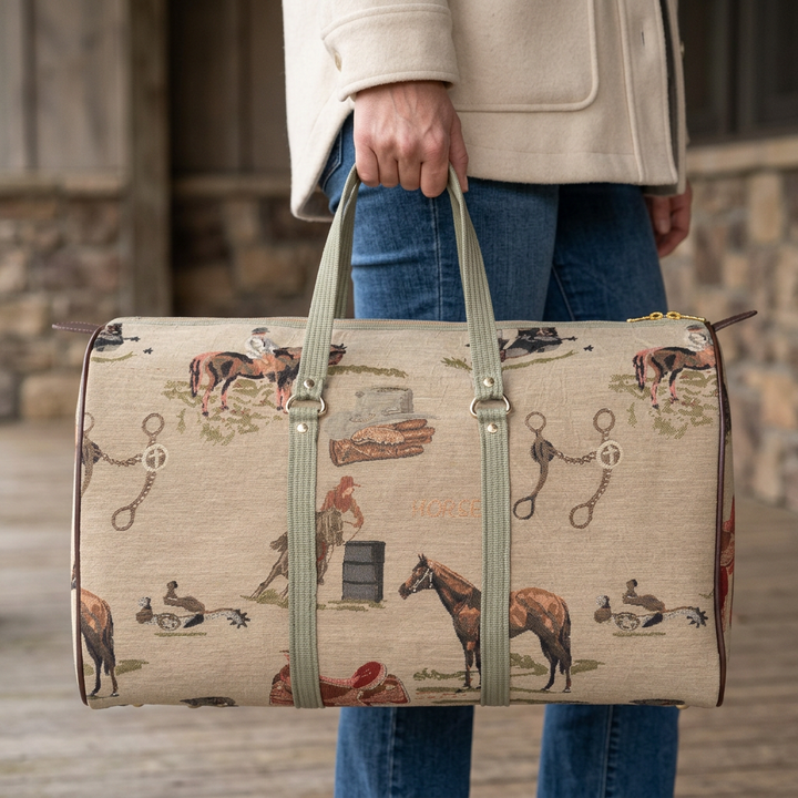 Western equestrian tapestry duffle carried by its green handles with a cream jacket and jeans.