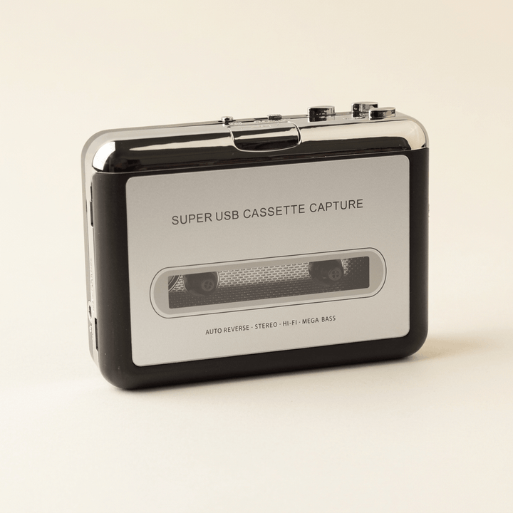 Silver-and-black portable USB cassette player with cassette window and chrome top controls on an ivory studio background.