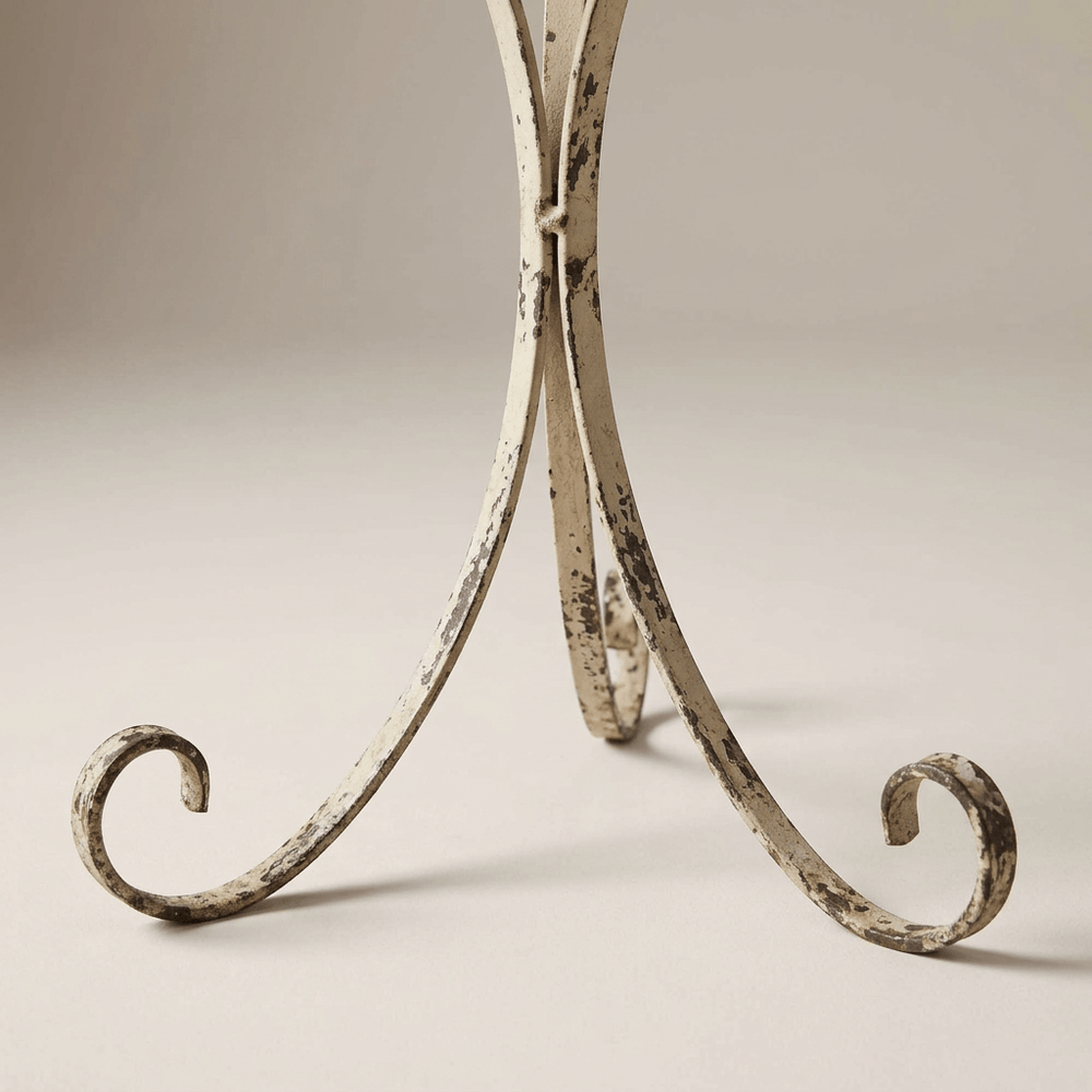 Close-up of the plant stand's curled iron feet and distressed pale painted finish.