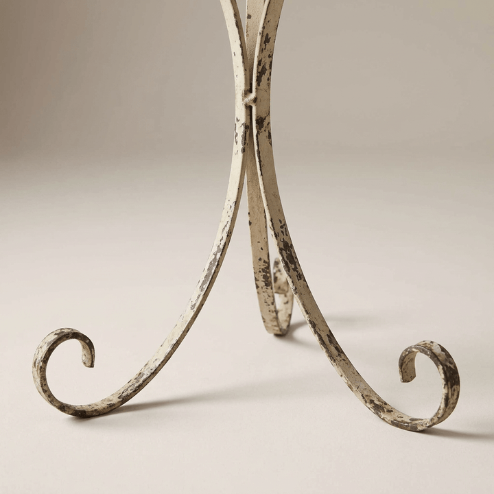 Close-up of the plant stand's curled iron feet and distressed pale painted finish.