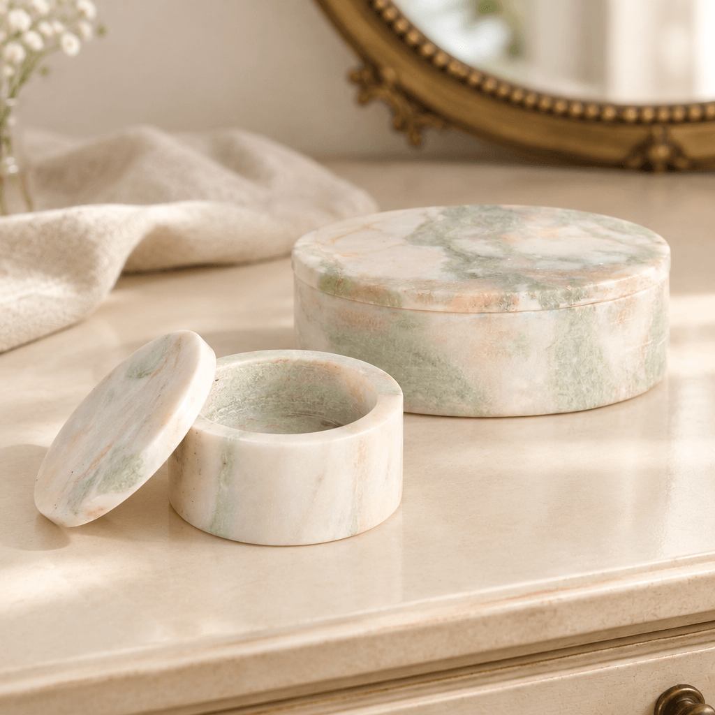 Marble boxes on a cream dressing table with the smaller box open and its lid beside it.