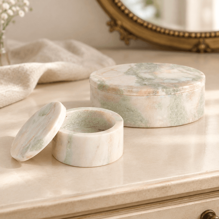 Marble boxes on a cream dressing table with the smaller box open and its lid beside it.