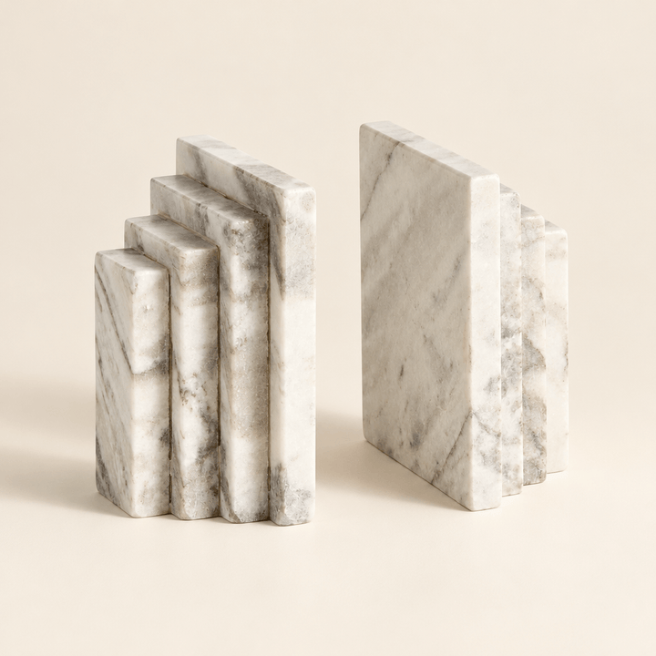 Pair of stepped marble bookends showing their tiered profiles and natural veining on an ivory background.