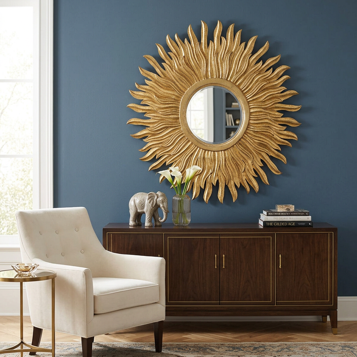 Aurelia Gold Sunburst Wall Mirror above a sideboard against a deep blue wall in a vintage glamour living room.