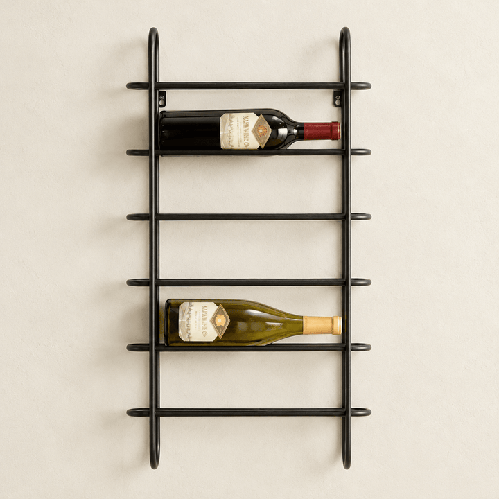 Black iron six-bottle wall wine rack mounted on an ivory wall with two wine bottles.