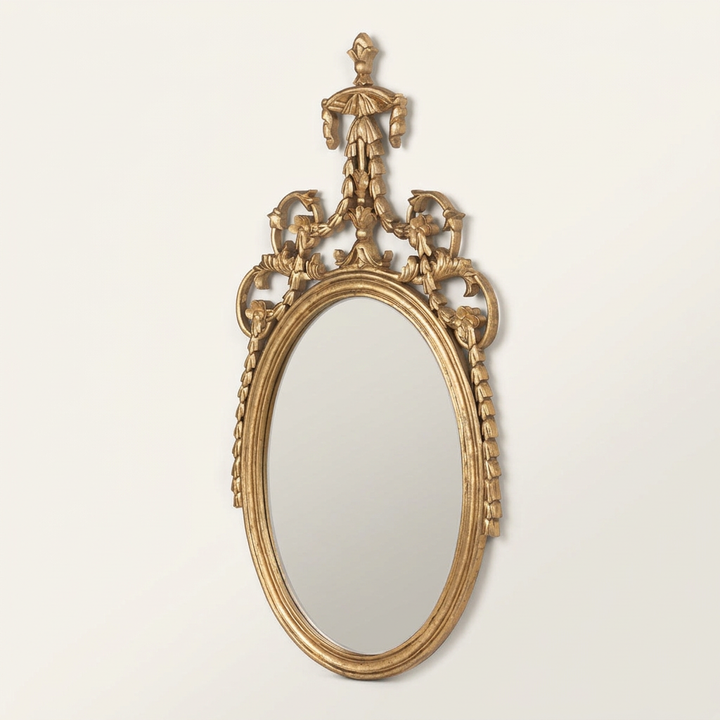 Antoinette Soft Gold Oval Wall Mirror with its full ornamental foliate crest against an ivory studio background.