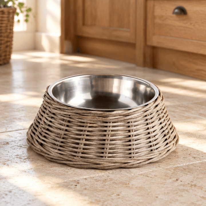 Gray rattan pet bowl with stainless steel insert styled on a pale stone kitchen floor.