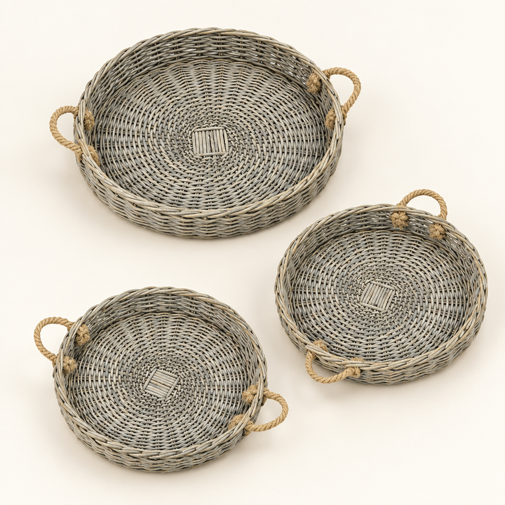 Three grey-washed round willow trays with jute handles on an ivory background