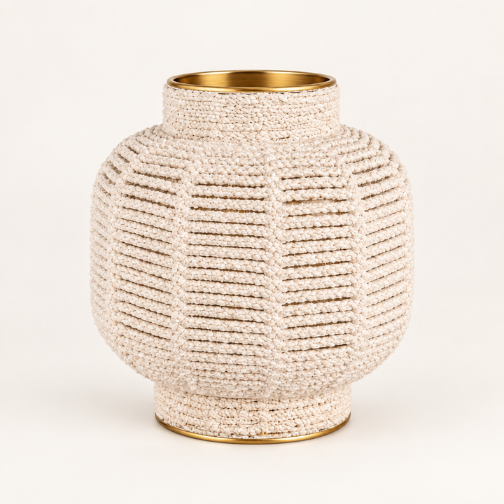 White macrame brass-finish vase on a warm white studio background