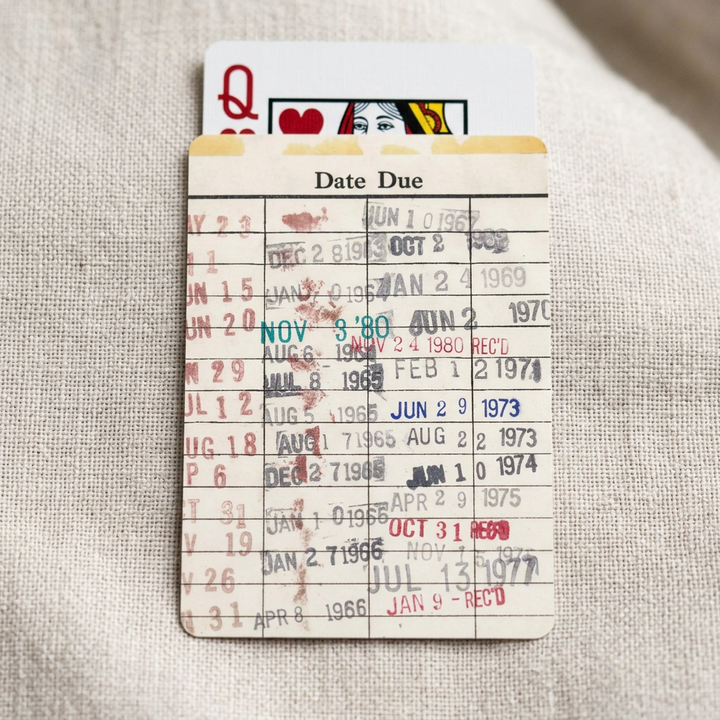 Close detail of cream Date Due card back with ruled grid and colorful vintage-style date stamps