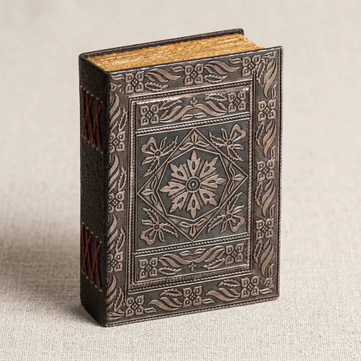 Close detail of silver floral embossed journal cover, red spine stitching, and aged page edges