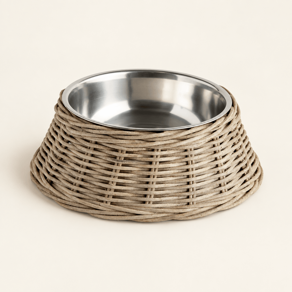 Large gray woven rattan pet bowl with stainless steel insert on an ivory studio surface.
