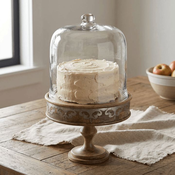 Belvedere Cake Pedestal with Glass Dome displaying a buttercream cake on a wood table.