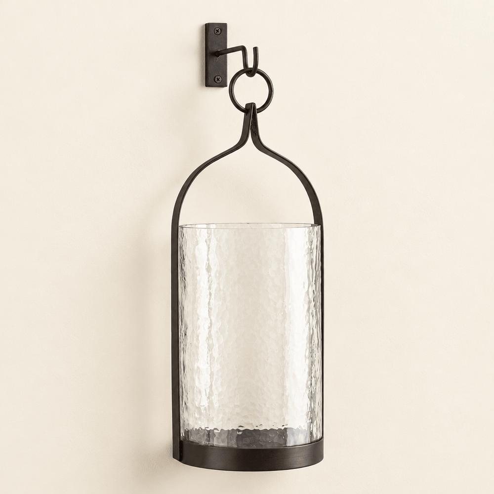 Black and bronze steeple iron lantern with hammered glass sleeve and included wall hook on an ivory wall