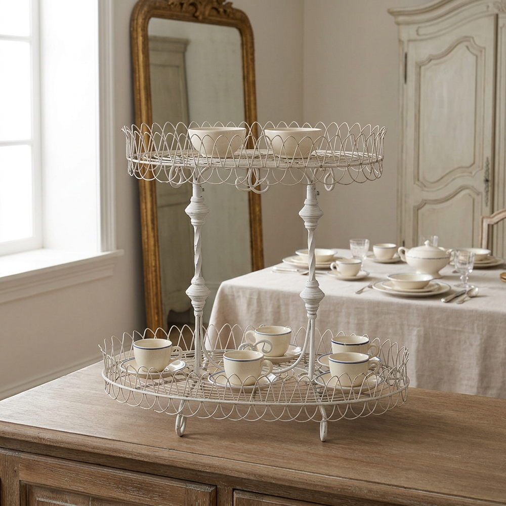 Fleury antiqued white wire stand displaying teacups, saucers, and bowls on a wooden sideboard.