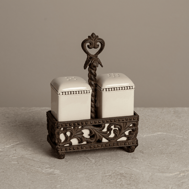 Bellavita salt and pepper set on a pale stone surface against a neutral taupe studio backdrop.