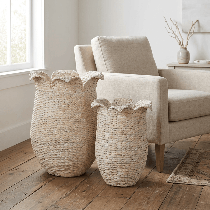 Petalweave whitewash storage baskets in two sizes beside a linen armchair in a light coastal living room.