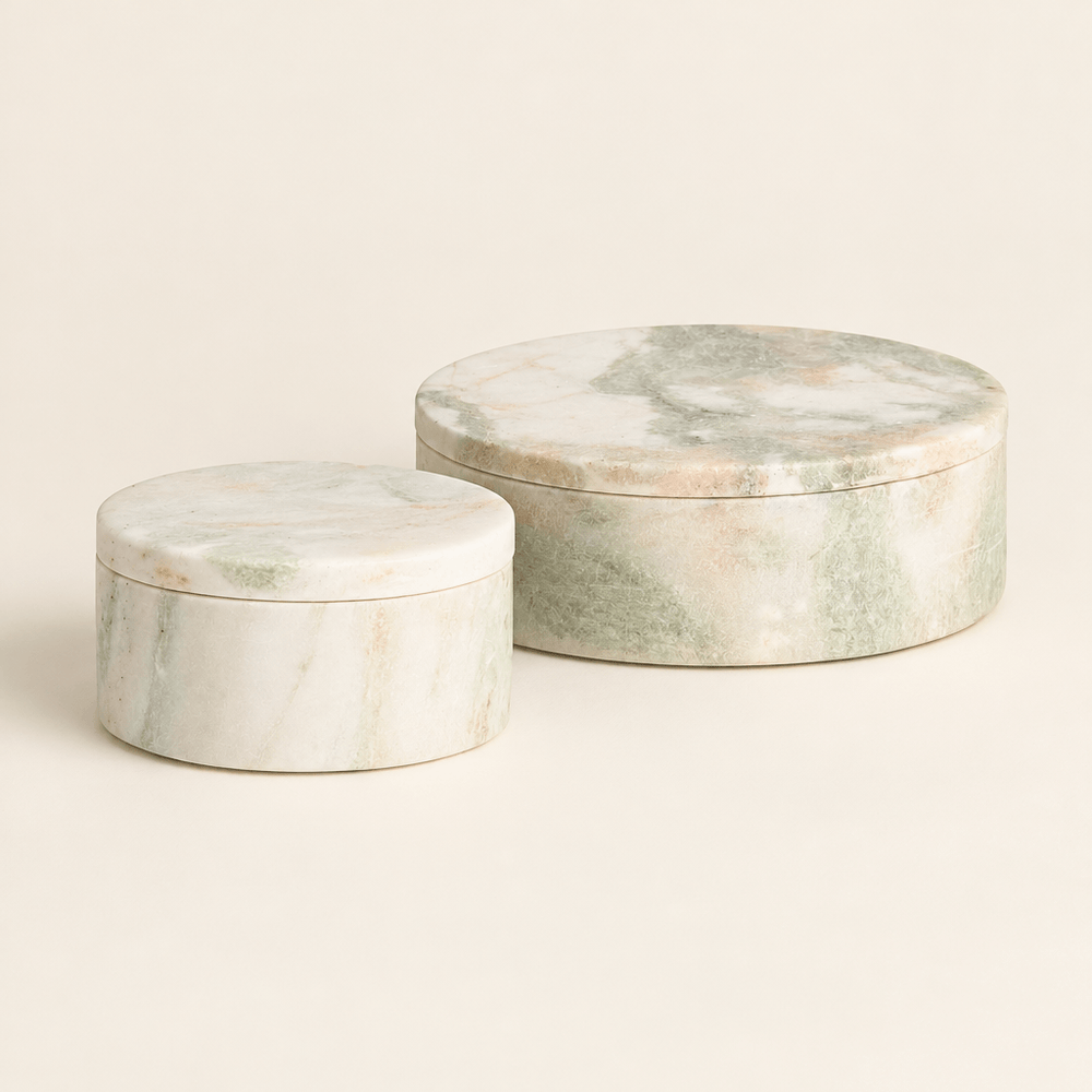 Two green and white round marble lidded boxes on an ivory studio background.