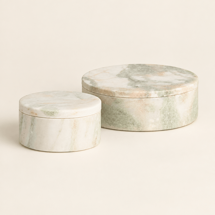 Two green and white round marble lidded boxes on an ivory studio background.