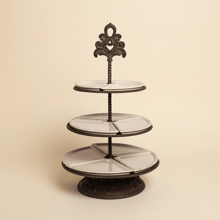 Bellavita three-tier server with cream ceramic serving dishes and ornate dark brown metal stand against an ivory backdrop