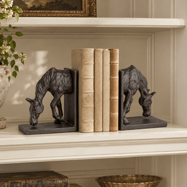 Pair of black bronze grazing horse bookends styled with books on a cream library shelf.